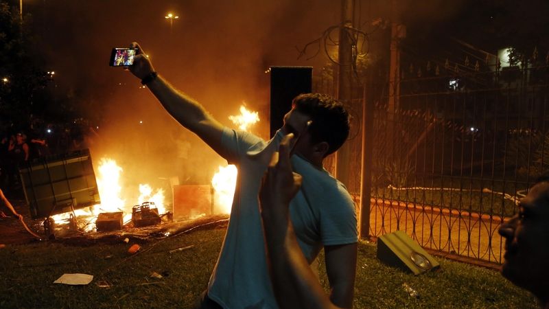 Demonstranti si děljí selfie před hořící budovou kongresu 