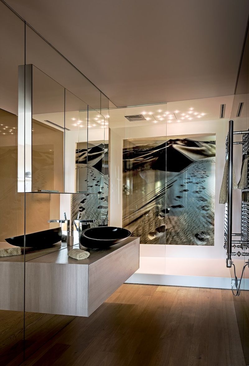 Sprchový kout koupelny zdobí fotografie z limitované edice Jiřího Machta s výjevem pouště, kterou majitel navštívil. Stěny jsou obloženy zrcadly a kaleným sklem. 