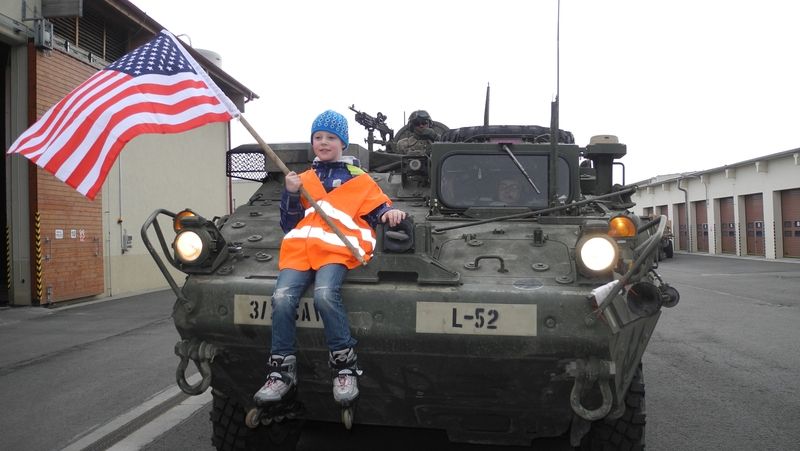 Malý chlapec se veze na americkém obrněném transportéru.