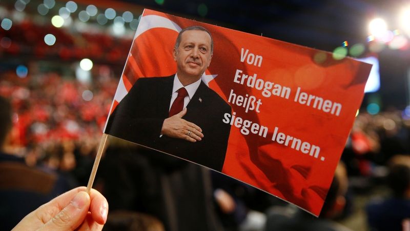Vlaječka na podporu tureckého prezidenta Recepa Erdogana na mítinku tureckého premiéra Binaliho Yildirima v německém Oberhausenu. Text říká: Učit se od Erdogana znamená učit se vítězit.