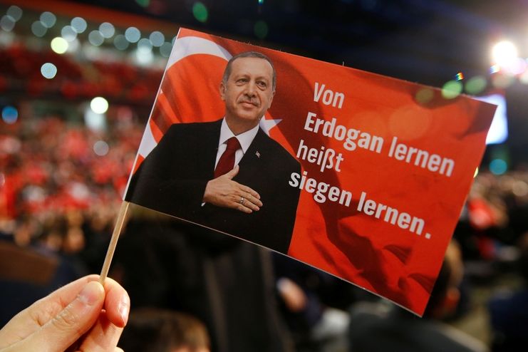 Vlaječka na podporu tureckého prezidenta Recepa Erdogana na mítinku tureckého premiéra Binali Yildirima v německém Oberhausenu. Text  říká: Učit se od Erdogana znamená učit se vítězit.