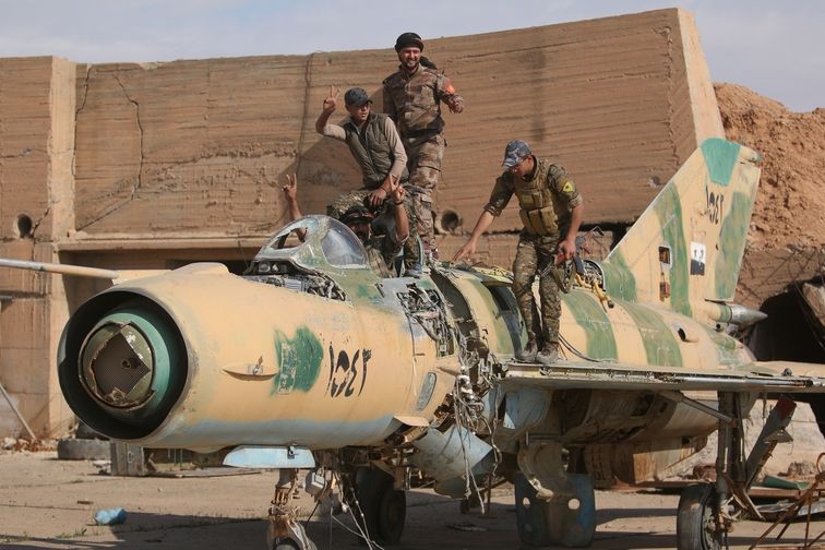 Bojovníci Syrských demokratických sil pózují na vraku syrského MiGu-21 na základně Tabka 