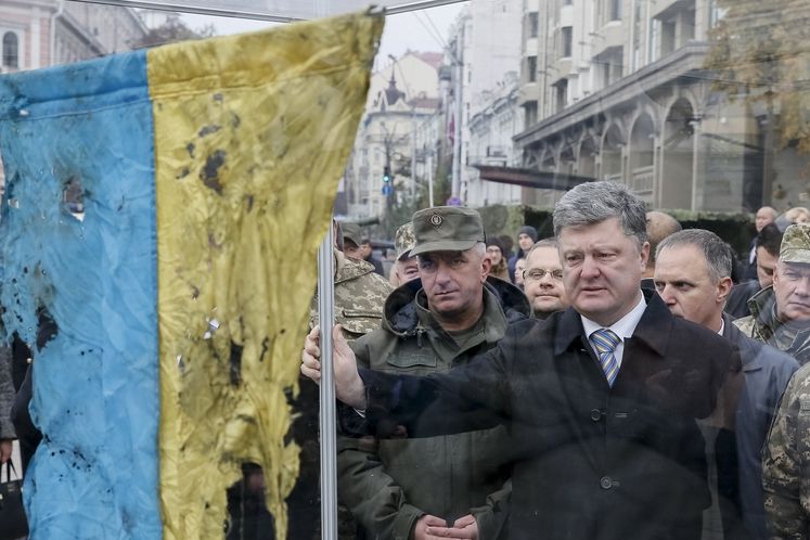 Ukrajinský prezident Petro Porošenko v Kyjevě s vlajkou přivezenou z oblasti bojů na východě Ukrajiny.