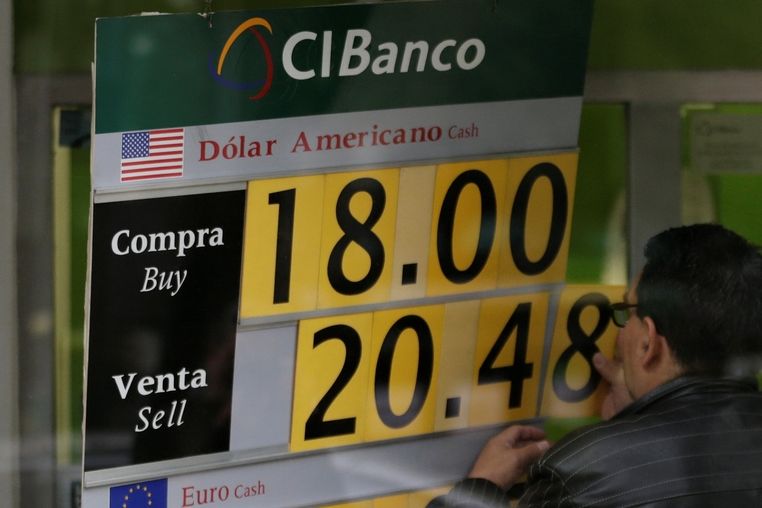 Zaměstnanec banky mění směnný kurz pesa za dolar v Mexico City.