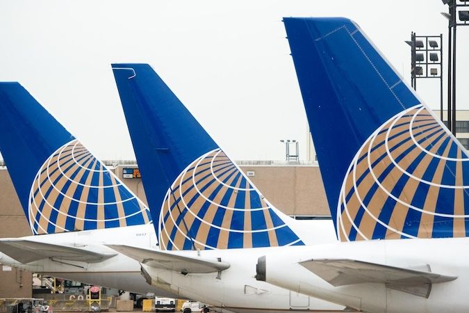 Několik letounů aerolinek United Airlines stojících vedle sebe na ranveji.