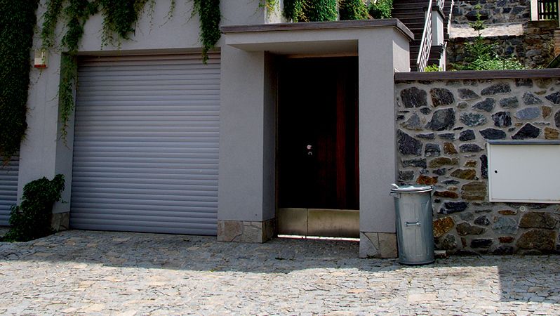 Vedle krytého minimalistického vstupu do vily nechybí garáž. 