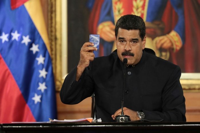 Venezuelský prezident Nicolas Maduro gestikuluje s venezuelskou ústavou v ruce.
