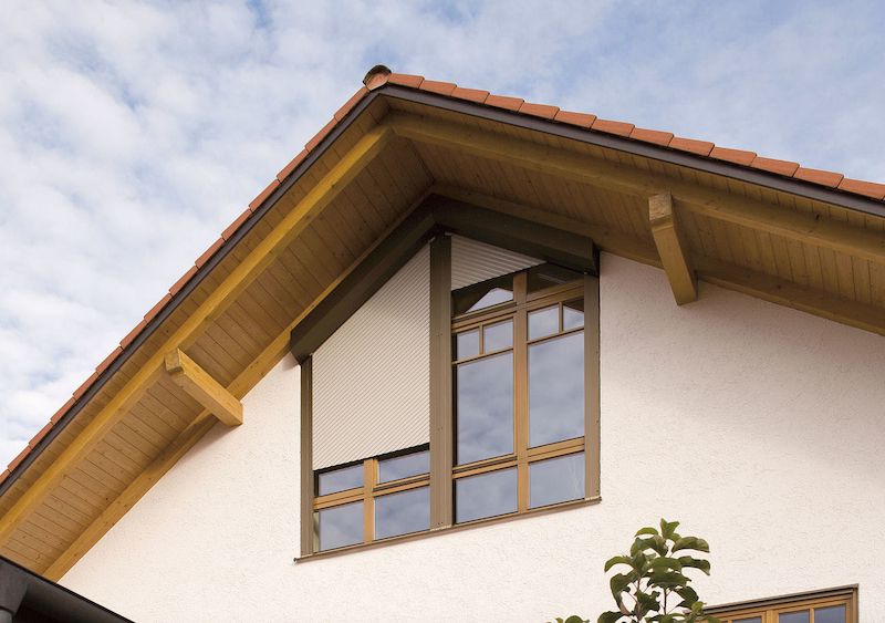 Tvarově atypické venkovní rolety brání slunečním paprskům průchodu štítovými okny do podkrovní části domu. 