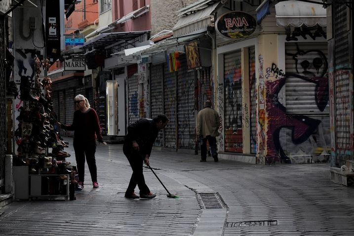 Muž uklízí časně ráno před obchodem v Aténách
