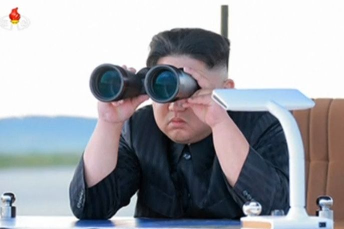 Kim Čong-un se dalekohledem dívá na raketu Hwasong-12.