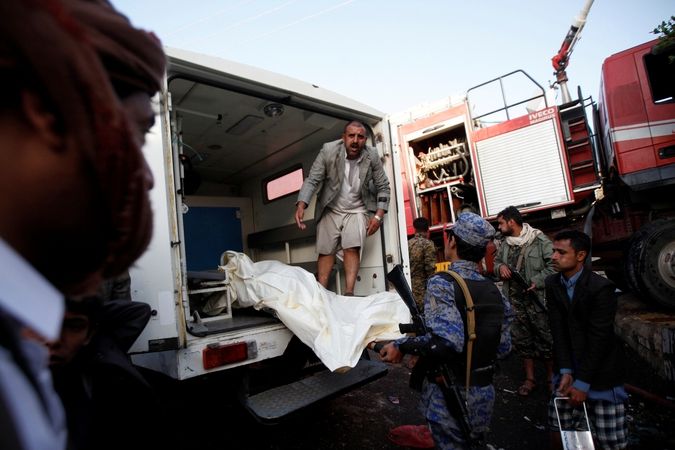 Lidé nakládají tělo jedné z oběti náletu na Saná 