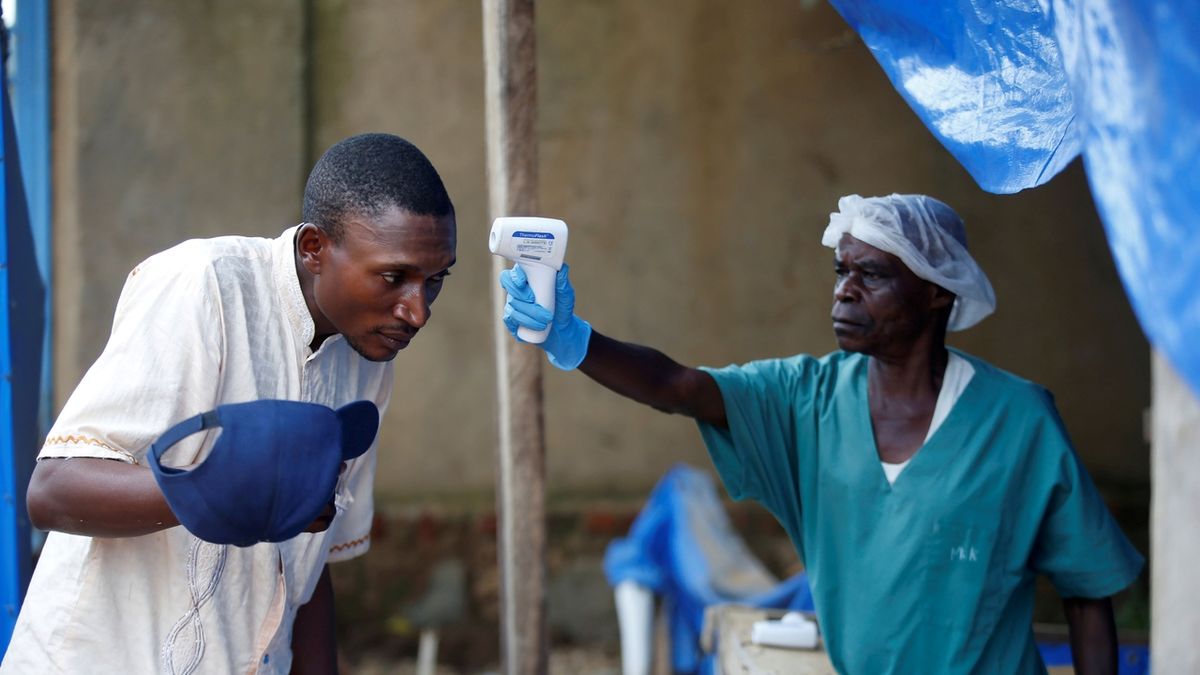 Zdravotník měří teplotu muži v centru pro ebolu v Beni.