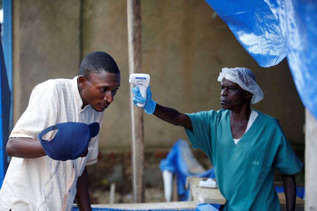Zdravotník měří teplotu muži v centru pro ebolu v Beni