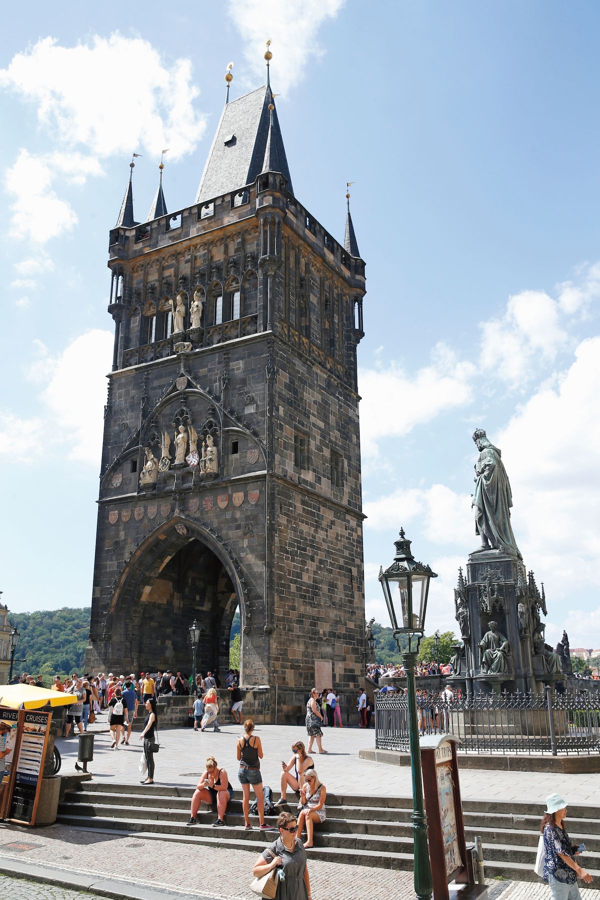 Vlevo Staroměstská mostecká věž, vpravo socha Karla IV. z roku 1848