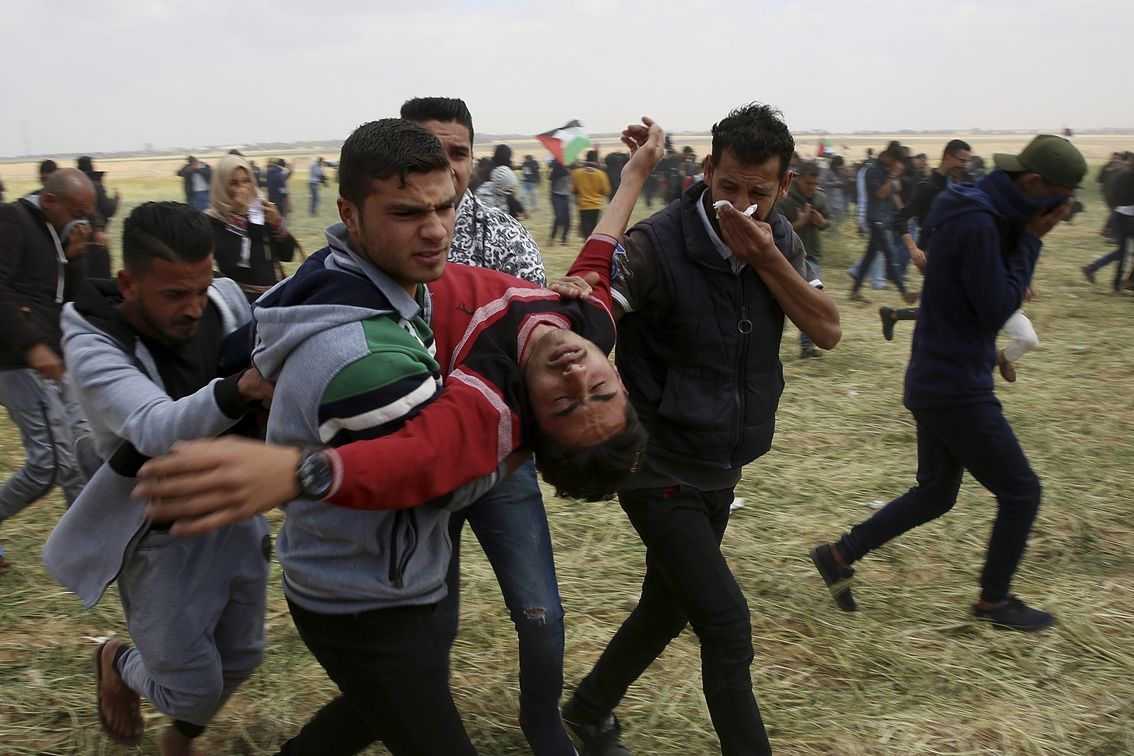 Palestinci odnášejí jednoho z účastníků protestů v Gaze zraněného při střetech s Izraelci