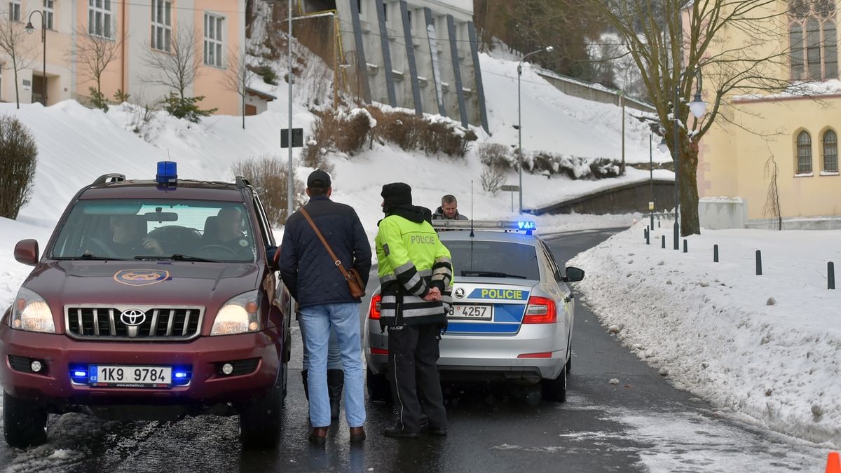 Policisté hlídkují u zátarasu v Jáchymově, kde silničáři uzavřeli sněhem zavátou silnici směrem na Boží Dar. 