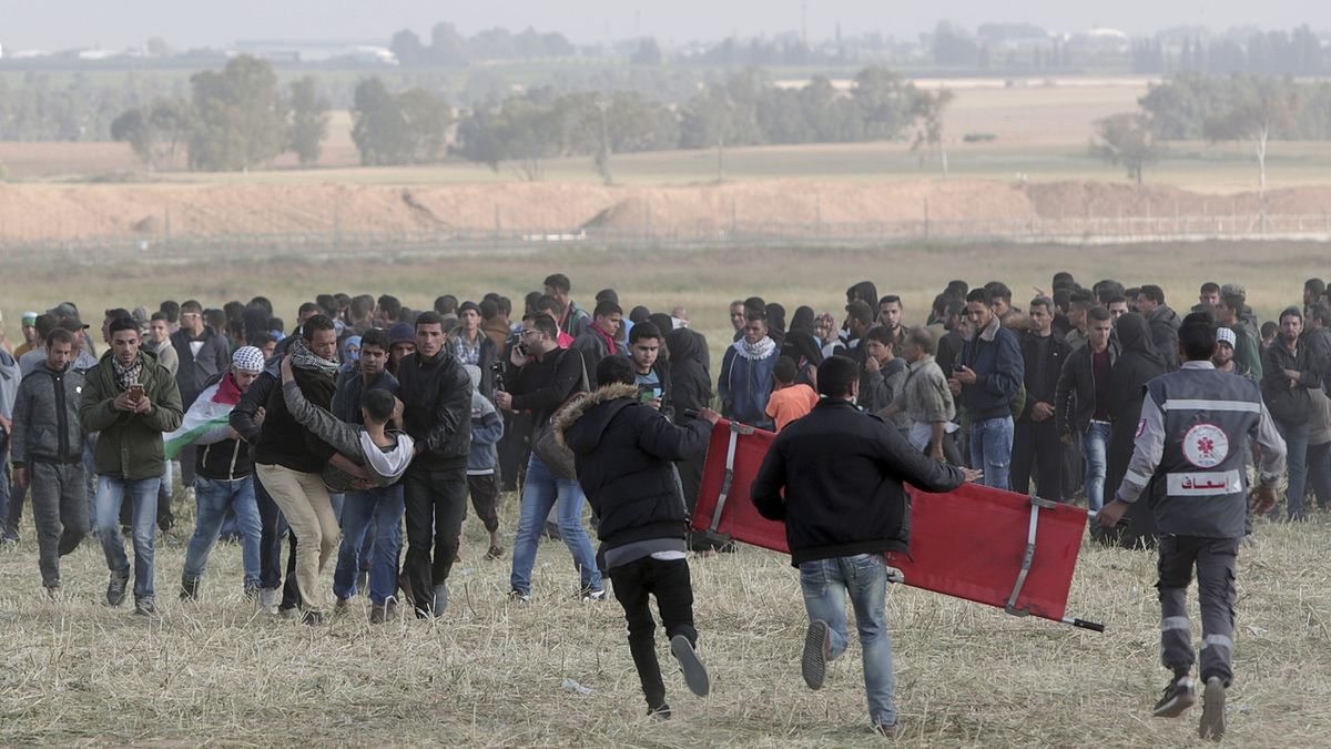 Palestinci odnášejí jednoho z účastníků protestů v Gaze zraněného při střetech s Izraelci