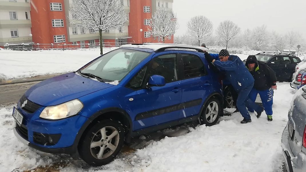 Lidé odtahují jeden z havarovaných vozů při hromadné nehodě ve Zlíně-Podlesí. 