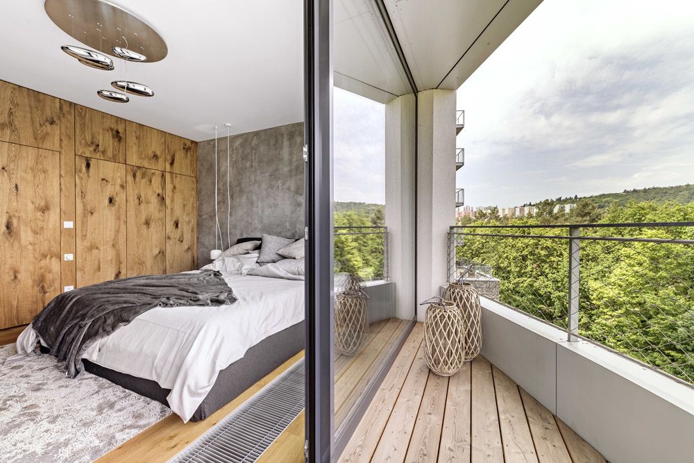 Prostor ložnice, která je ukázkou delikátní kombinace velkoplošné prezentace dřeva a betonové stěrky, získává na hodnotě také díky terase, se kterou je místnost propojena.
