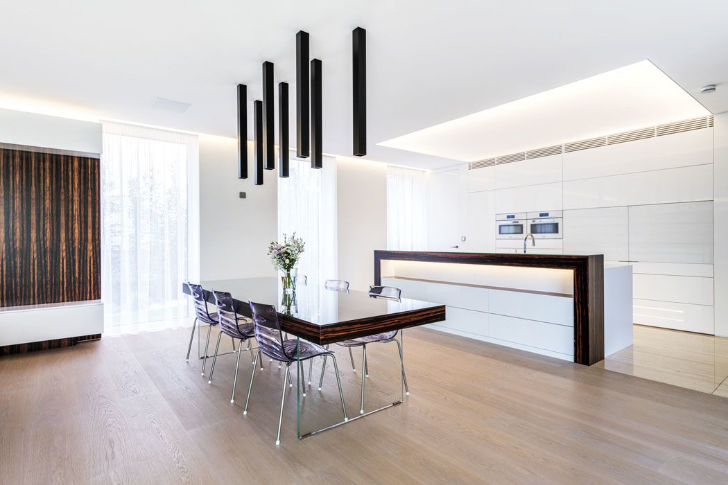 Bíle lakovaná kuchyňská linka se skládá z kompaktní sestavy u stěny (s integrovanými dveřmi do technické místnosti) a ostrovního varného centra. Má příjemné rozptýlené osvětlení – LED zdroje jsou zapuštěny ve stropním podhledu za průsvitnou fólií Barisol.