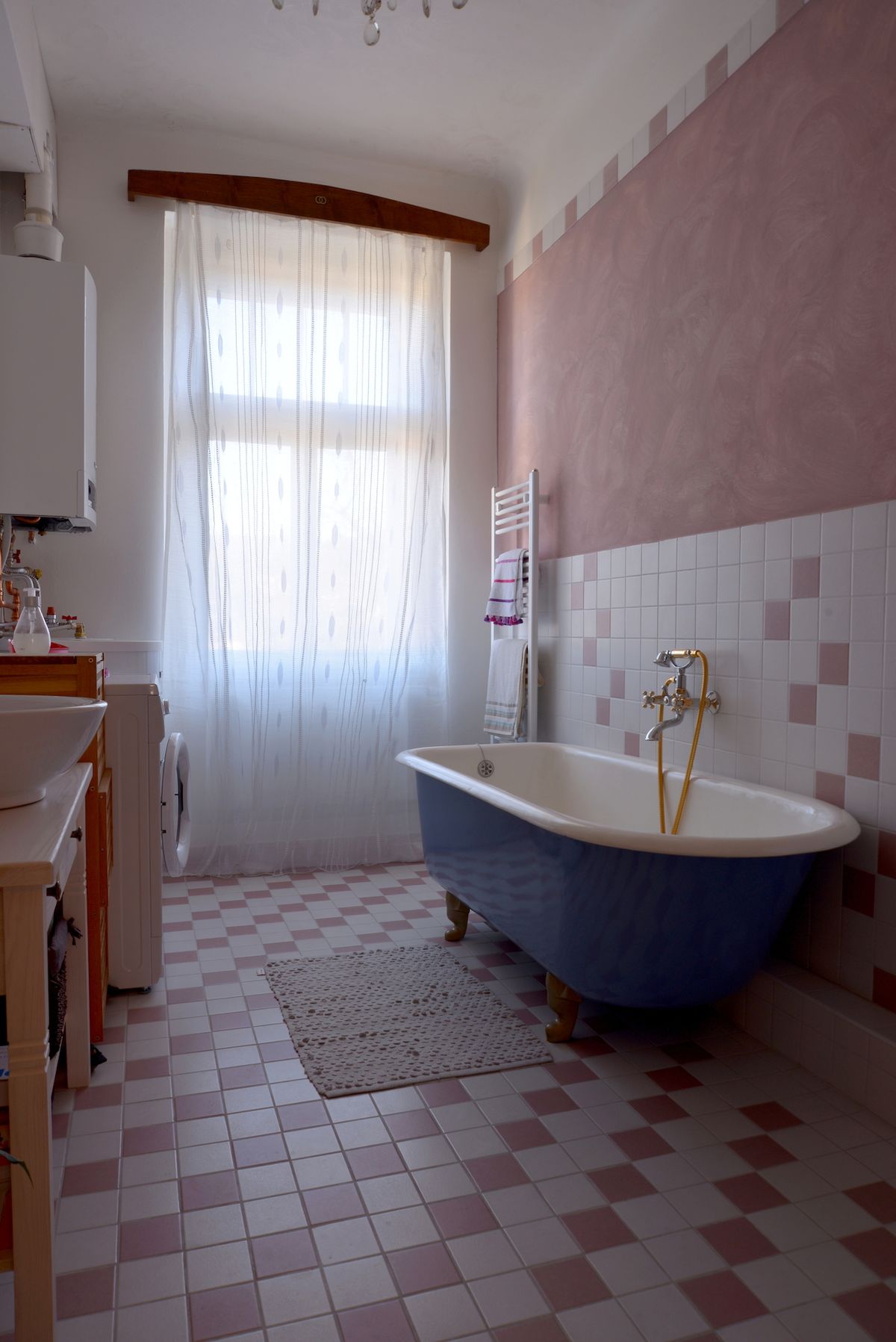 Dominantou růžovo bílé koupelny je modrá litinová vana z roku 1924.