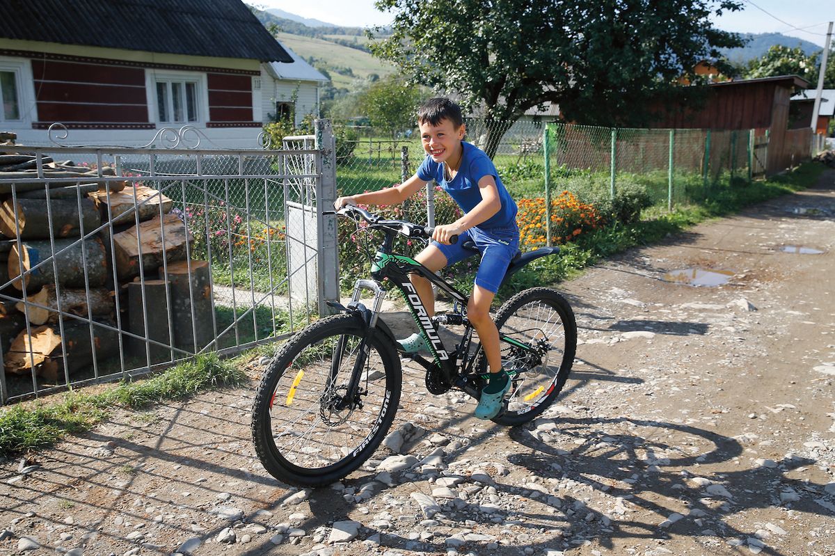 Vitja sedí na novém kole, na které si vydělal sběrem borůvek bratr Dima.