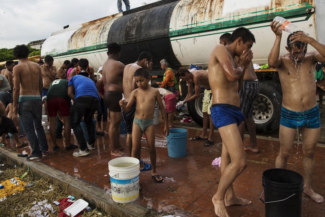 Migranti ze Střední Ameriky v Mexiku provádějí u cisterny ranní hygienu.