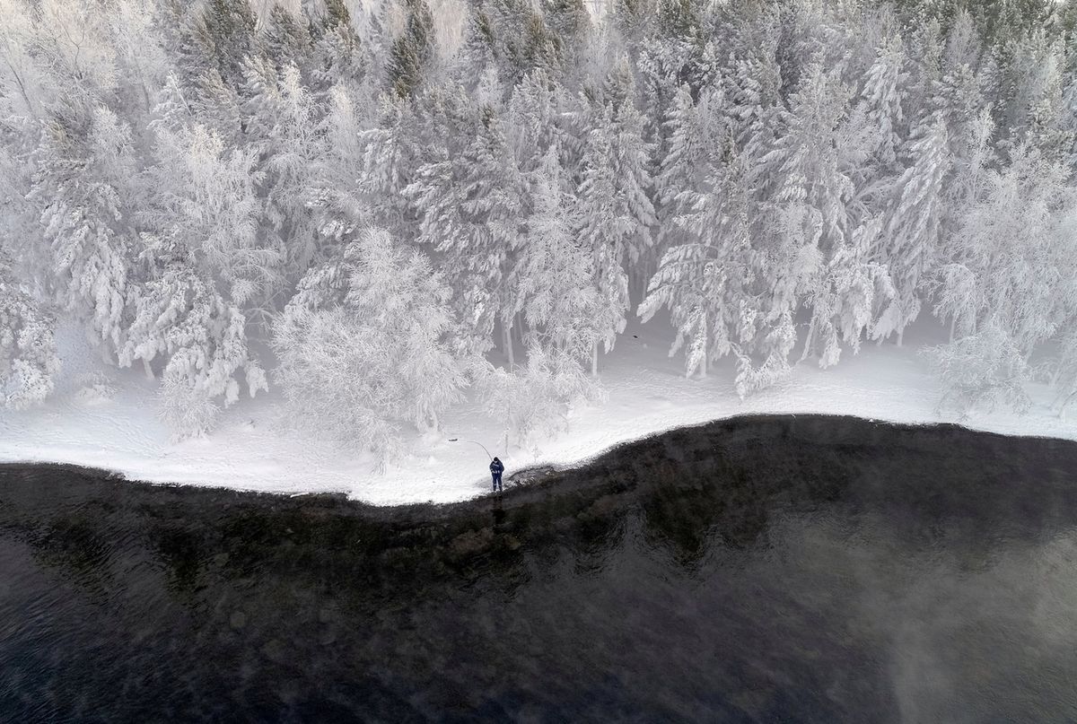 Muž rybaří při teplotě minus 16 stupňů Celsia na břehu řeky Jenisej nedaleko sibiřského města Krasnojarsk v Rusku. 