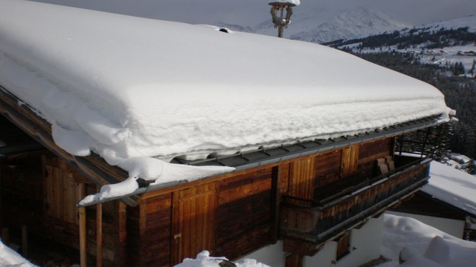 Na střeše s nízkým sklonem v Alpách většina sněhu zůstane a nesjíždí.