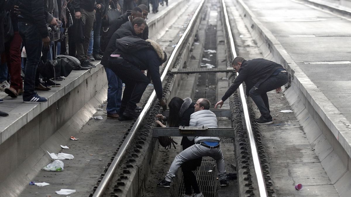 Cestující pomáhají ženě, která spadla z přeplněného nástupiště na jednom z pařížských nádraží.
