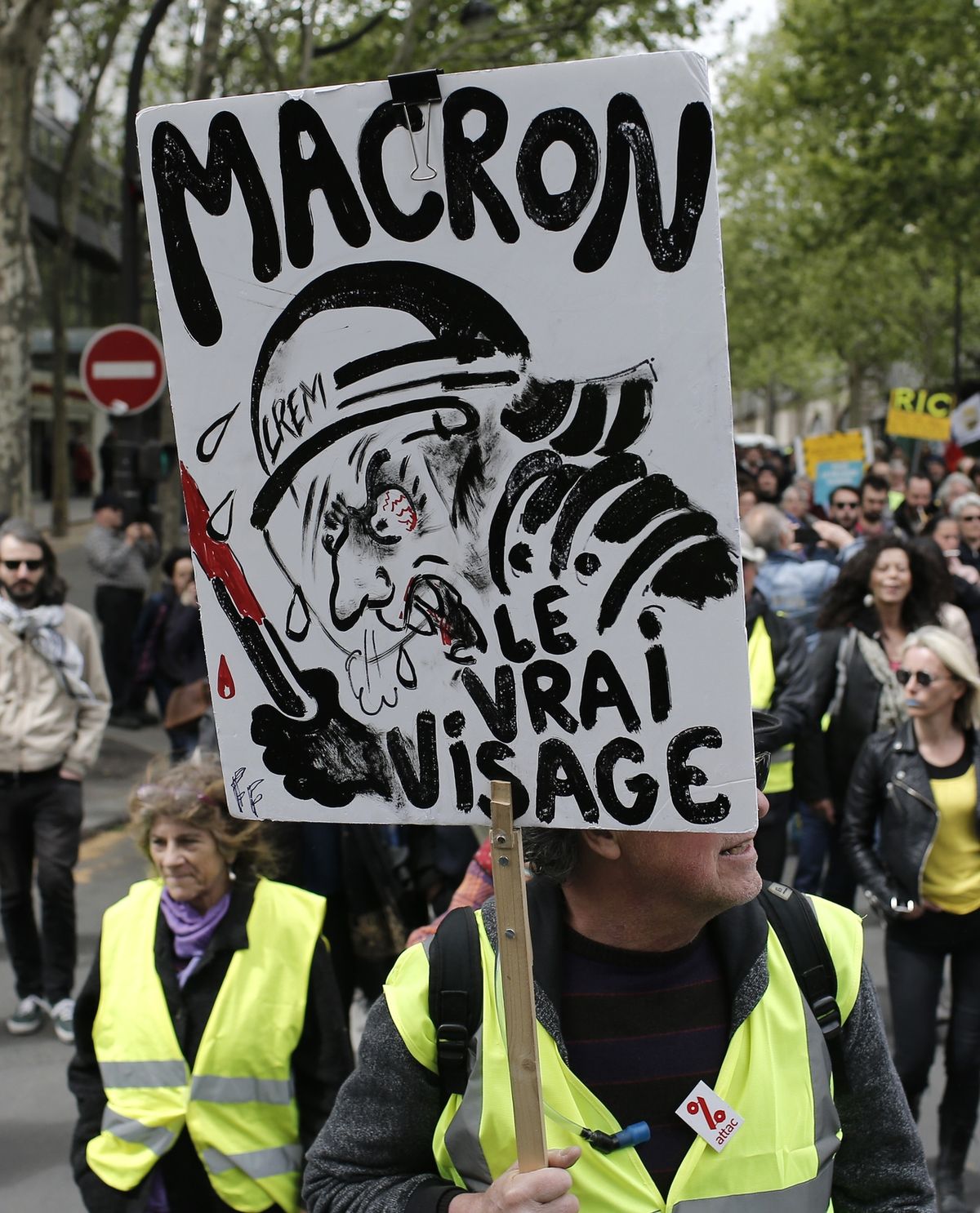 Macron, jeho skutečná tvář, stojí na transparentu žlutých vest