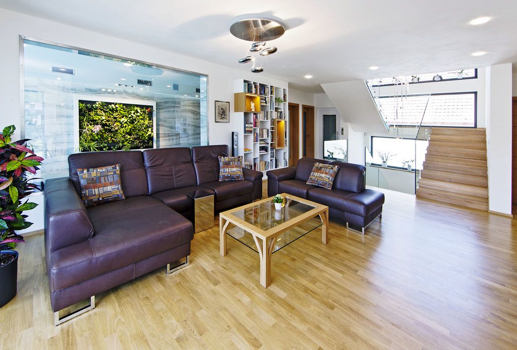 Obývací pokoj má podobu otevřené haly propojené se schodištěm, kuchyní i s bazénem. Prosklenou stěnou je dokonce vidět z lehátek u bazénu na televizi v obýváku.