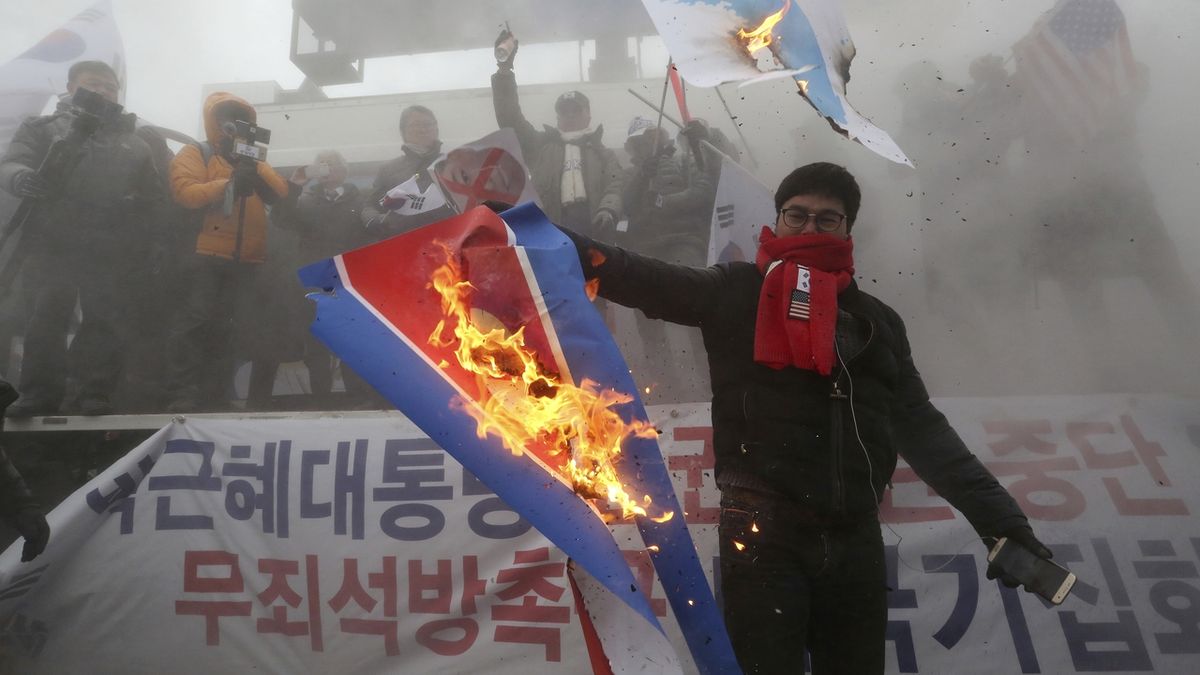 Jeden z demonstrantů pálí severokorejskou vlajku.