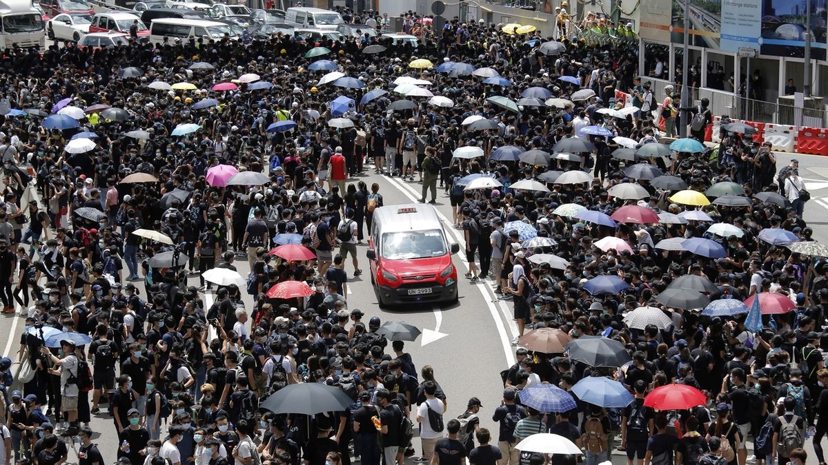 Taxík projíždí davem demonstrantů v Hongkongu 