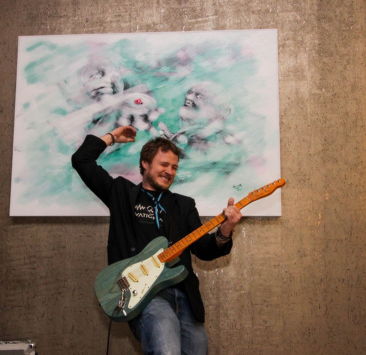 Honza Homola hrál na vernisáží svých obrazů na kytaru.