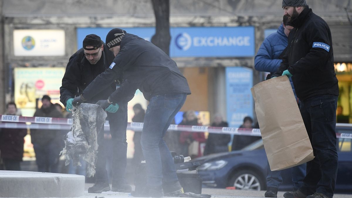 Policejní technici odnášejí ohořelý oděv od sochy sv. Václava na Václavském náměstí v Praze
