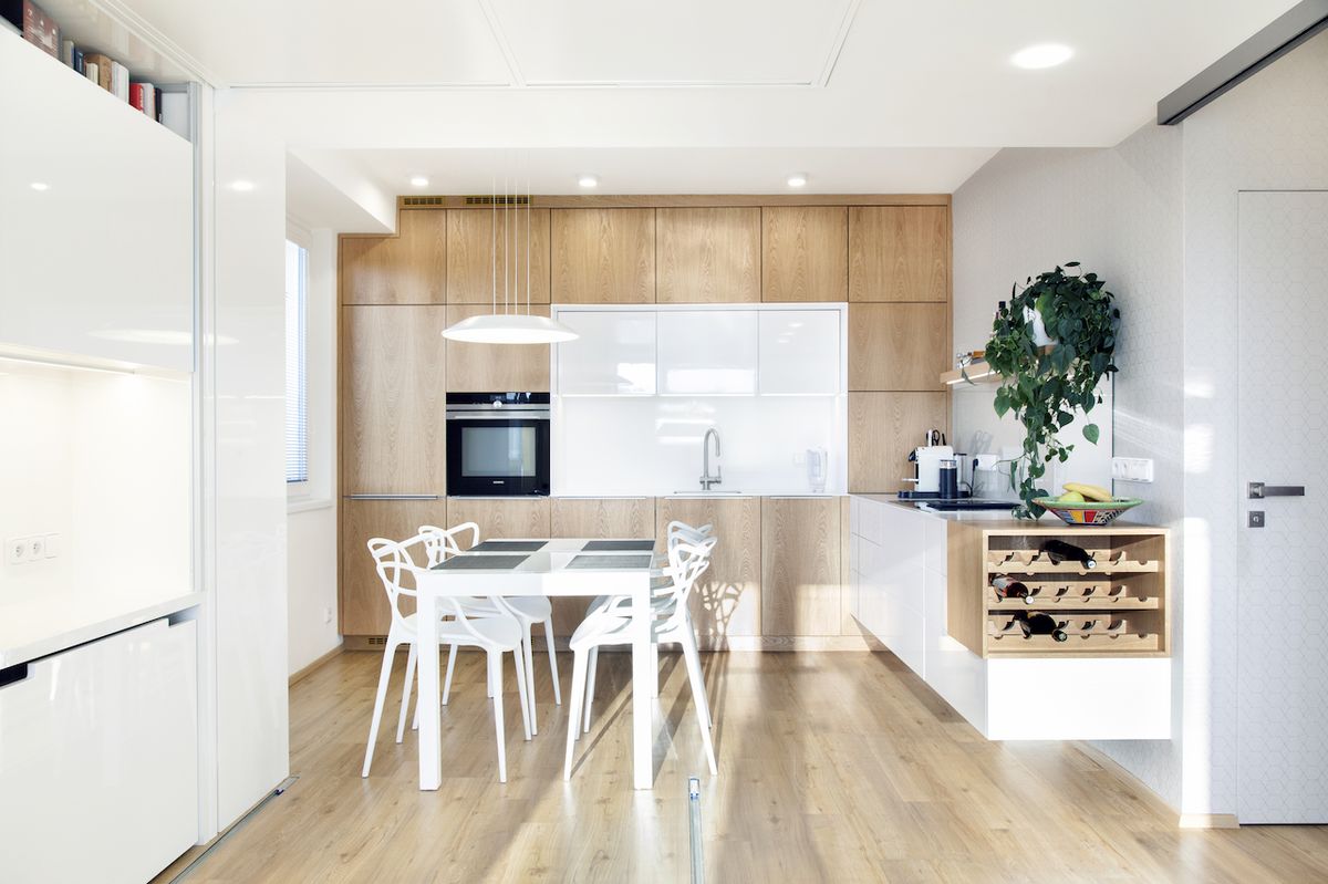 Použití dekoru dřeva na podlaze, ale i kuchyňské lince ladí s bílými povrchy ostatních atypických nábytků a prostor opticky zvětšuje.