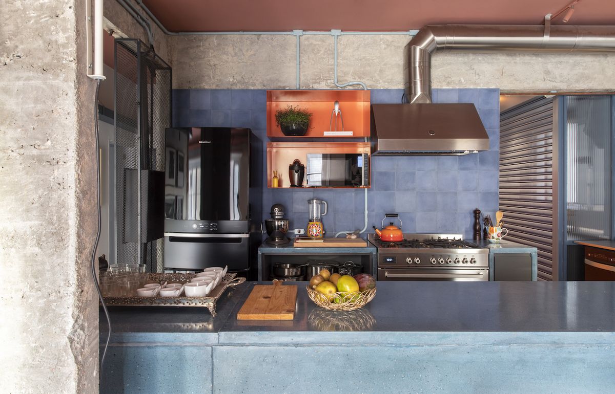 Přiznané betony tvoří pozadí pro do modra laděnou kuchyň, jíž dominují pracovní plochy z pigmentovaného betonu.