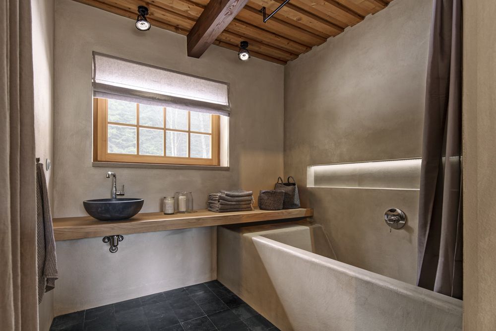 Koupelna nabídla dostatek prostoru k umístění vyzděné vany ošetřené stěrkou, která je i na stěnách. Podlahu kryje kámen. 