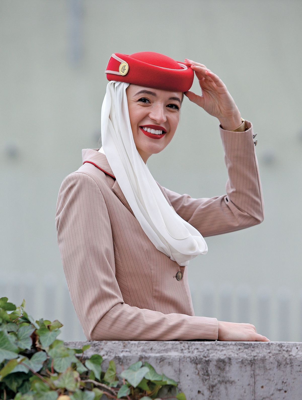 Jana Kůtová hrdě obléká béžovou uniformu Emirates s bílým šátkem, typickým rudým kloboučkem a stejně barevnou kabelkou. „Rudá rtěnka je také součástí uniformy, ale odstín si vybíráme samy.“