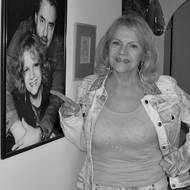 Eva Pilarová ve svém bytě, na plakátě se svým manželem Janem Kolomazníkem.