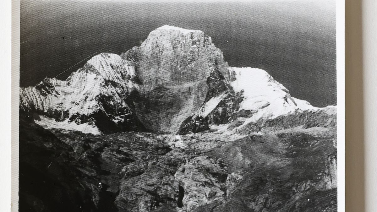 Snímek zachycuje horu, z níž se při zemětřesení utrhnul vrchol. Ten z velké části spadl do jezera. Masa kamení, bláta a vody následně pohřbila tábor.