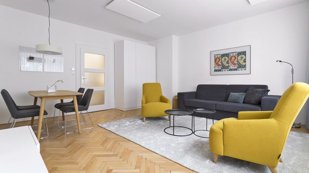 Materiálové a barevné řešení interiéru je postavené na kombinaci přírodních barev a dubového dřeva. Oživující barevný akcent dodávají hlavní obytné místnosti dvě žlutá křesla a obrazy na stěnách. Součástí obývacího pokoje je i jídelna.