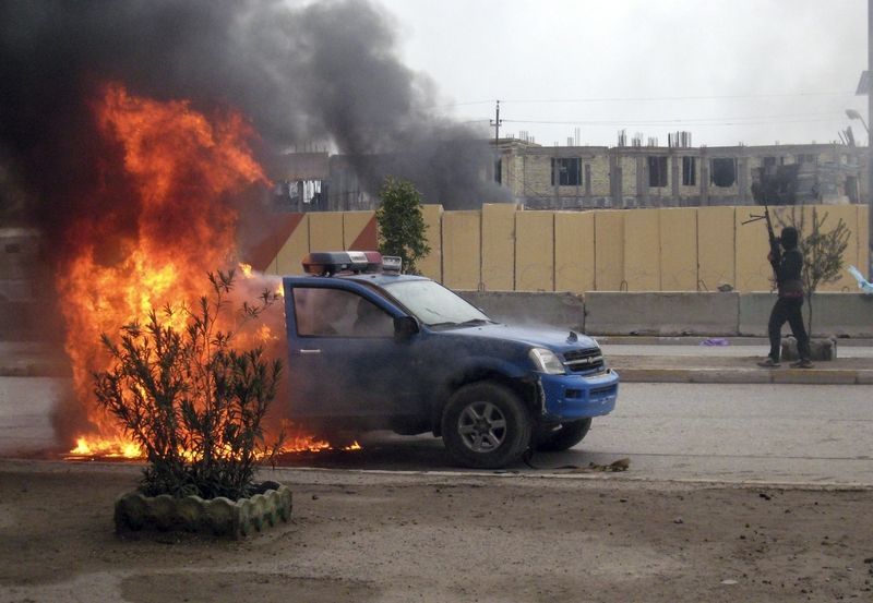 Bojovník Al-Káidy u hořícího policejního vozu v Ramádí 