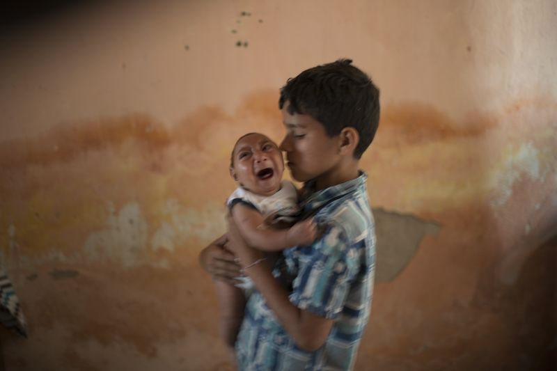 Desetiletý chlapec drží svého dvouměsíčního bratra, který se narodil s mikrocefalií.