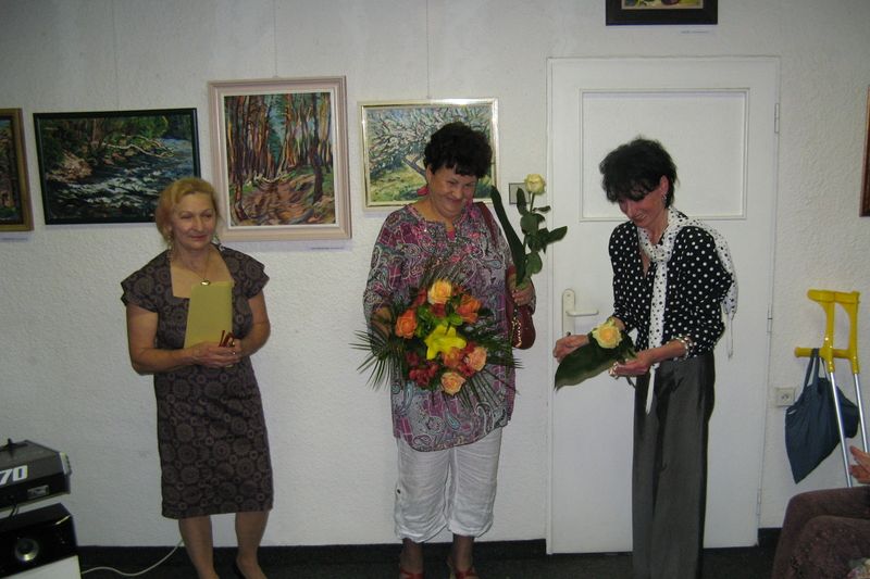 Olga Hrachová (uprostřed) přebírá na vernisáži květiny 