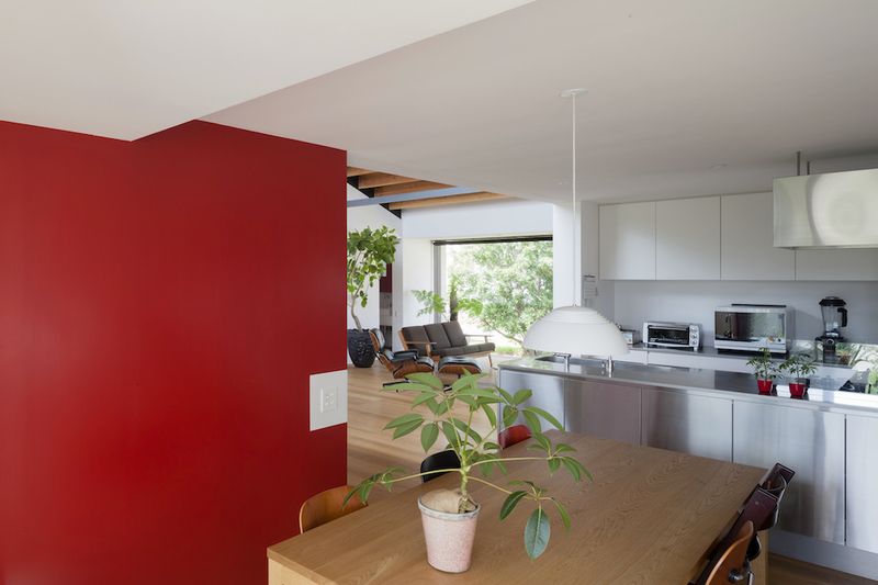 Kuchyň s jídelním stolem je jako jediná část domu oživena sytou červenou barvou stěny a několika doplňků.