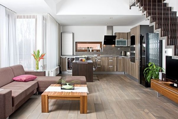 Oblíbeným interiérovým trendem posledních měsíců je kombinování několika druhů dřeva v odlišných barevných odstínech, což zvládli manželé výborně. Výsledkem je teplá a harmonická atmosféra v nejčastěji používaném prostoru.