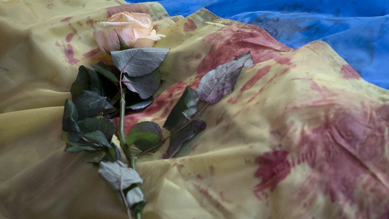 Růže na vlajce, která zakrývá jednu z obětí.