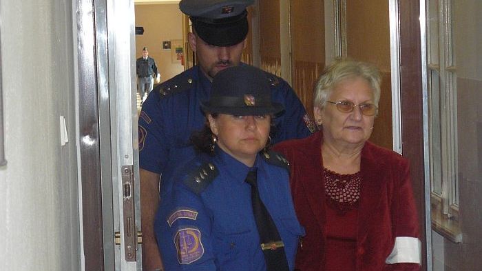 Eskorta přivádí Marii Vítovcovou do soudní síně.